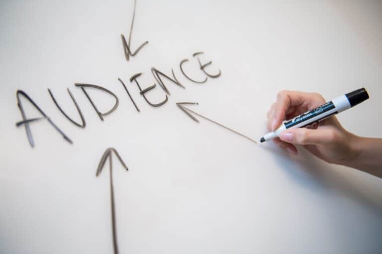 The words "Audience"written in capital letters on a white board to explain why you must know your target audience in marketing.